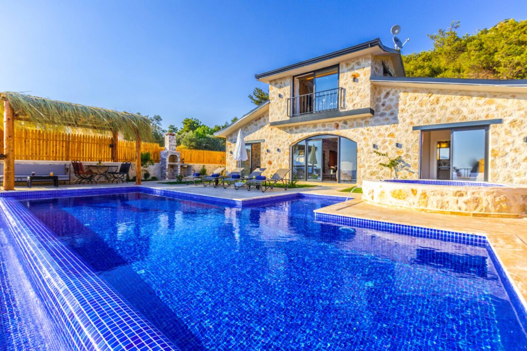 A beautiful stone villa with a stunning blue pool and lush greenery.