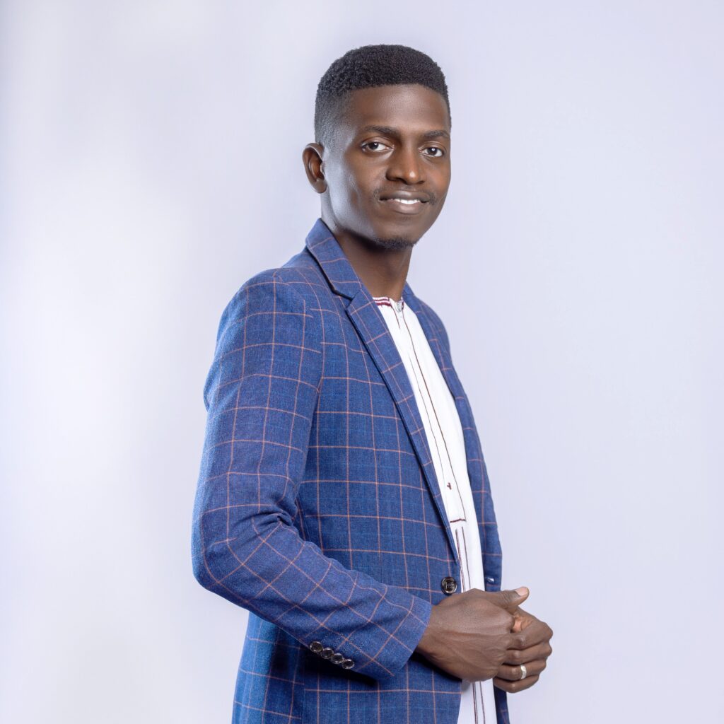Stylish portrait of a confident young man in a blue checked suit against a neutral background.