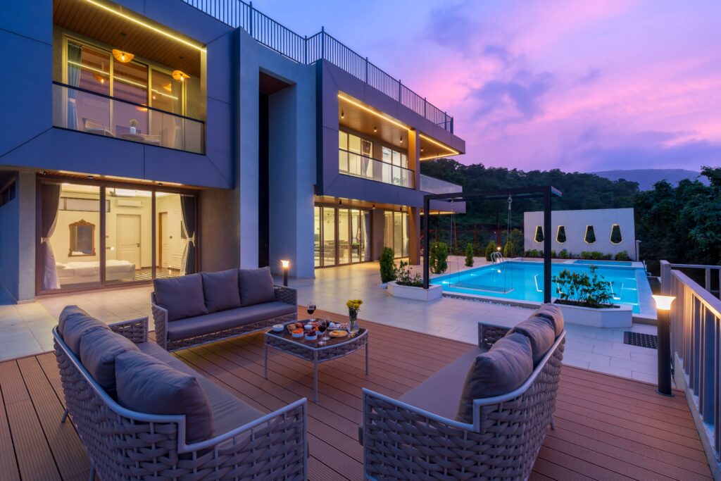 Stunning modern villa with outdoor seating and pool, captured at sunset.